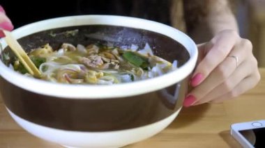 Güzel bir genç Asyalı kız bir Asya kafede Pho çorba bir fotoğraf alır. Çin, Vietnam veya Japon Kafe veya Restoran