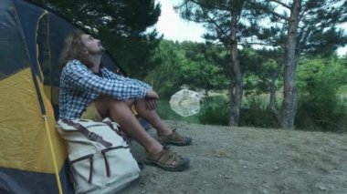 Kamp ve arkadaşlar ile seyahat yürüyüş. Bahar sabahı sahne açık, adam çadırda oturan gökyüzüne bakar, tatil hakkında düşünme gülümseme. Dostluk konsepti ve dünya turu
