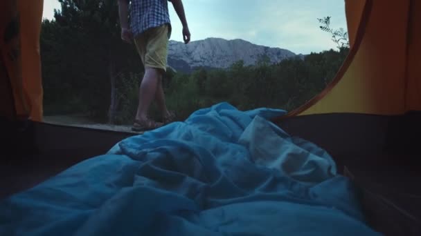 Un jeune randonneur se tient près de la tente, près du lac. Grande araignée forestière. Mode de vie actif. Portant une chemise à carreaux et un chapeau de voyageur. Concept de randonnée pédestre. Succès du lac de montagne . — Video