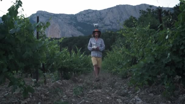 Egy férfi gazdálkodó használ egy drone a gazdálkodás. Felügyeli a szőlő mezőit. Új mezőgazdasági technológiák — Stock videók