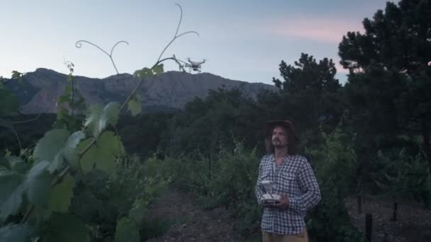 Un agriculteur utilise un drone pour l'agriculture. Surveille ses champs de raisin. Nouvelles technologies dans l'agriculture. Le copter regarde le pilote — Video