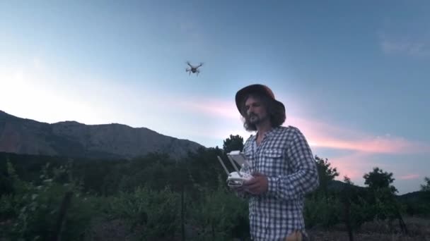 Een mannelijke boer gebruikt een drone voor de landbouw. Bewaakt zijn druiven velden. Nieuwe technologieën in de landbouw. De helikopter kijkt naar de piloot — Stockvideo