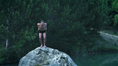 Bir yaz tatili ya da tatil bir dağ ormanı gölünün ortasında bir taştan atlama genç bir adam. Soğuk taze berrak suya atlar, doğal bir sokak yaşam tarzı.