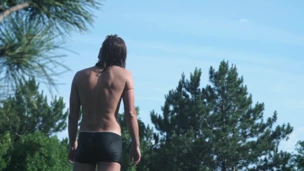 Un joven en unas vacaciones de verano o de vacaciones saltando de una piedra en medio de un lago de bosque de montaña. Salta al agua fría y clara, un estilo de vida callejero natural . — Vídeos de Stock