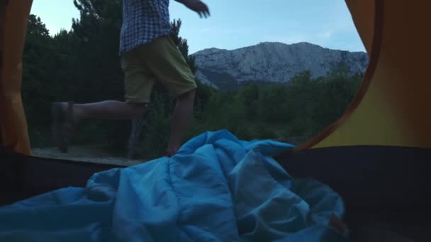 Un jeune randonneur se tient près de la tente, près du lac. Grande araignée forestière. Mode de vie actif. Portant une chemise à carreaux et un chapeau de voyageur. Concept de randonnée pédestre. Succès du lac de montagne . — Video
