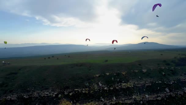 Gleitschirmflieger fliegen während des Extremsportwettbewerbs Gleitschirmfliegen über atemberaubende Bergketten. Gleitschirme fliegen bei Sonnenuntergang in den Bergen — Stockvideo