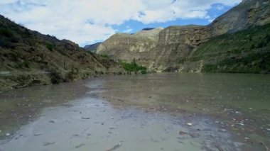 Kirli bir nehir suyunda plastik şişeler. Bir dağ nehrinde çeşitli çöpler. Çevrenin kirlenmesi. Ekoloji sorunları ve yok olma tehditleri. Havadan görünüm, insansız hava aracı görünümü.