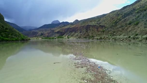 Kirli bir nehir suyunda plastik şişeler. Bir dağ nehrinde çeşitli çöpler. Çevrenin kirlenmesi. Ekoloji sorunları ve yok olma tehditleri. Havadan görünüm, insansız hava aracı görünümü. — Stok video