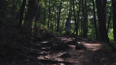 Ayağın botta yakın çekim. Bir adam yürüyüşçü yaz ormanında yol boyunca çalışır. Gün batımında ormanda yürüyüşçü. güzel bir Alman ormanında gün batımında muhteşem manzaranın tadını çıkaran yürüyüşçüler.