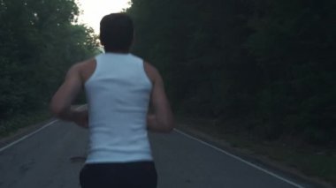 Yağmurlu akşamlarda doğada koşan bir adam. Erkek koşucu ormanda çam arasında bir otoyolda alacakaranlıkta bir çalışma yapıyor. Aktif bir spor yaşam tarzı meşgul. Vücudunuzu güçlendirir. Doğada spor
