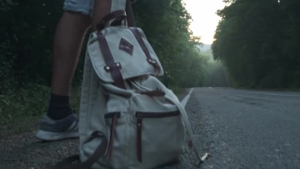 Un voyageur ramasse son sac à dos. Backpacker homme soulève son sac de la route dans le fond de la campagne du matin. Commence son voyage. 4K — Video