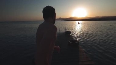 Genç milenyal otantik hipster adam muhteşem doğal c, temiz taze kelime ile dağ alp Gölü ahşap tahta üzerinde hızlı çalışır. komik bomba şekilde atlar. Yaz gezisi zevk alır.