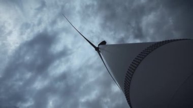 Rüzgar Türbinleri'nin yanındaki genç bir adam ekolojik enerji üretiyor. Çevre kirliliği kavramı, alternatif enerjinin yeni teknolojileri. Genel plan, akşam, bulutlu.