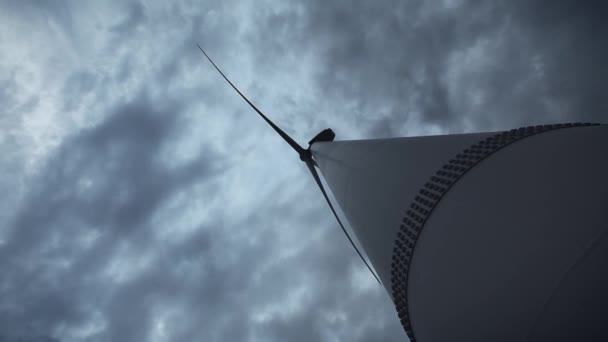 Een jonge kerel naast de wind turbines, produceren ecologische energie. Het concept van milieuvervuiling, nieuwe technologieën van alternatieve energie. Algemeen plan, avond, bewolkt. — Stockvideo