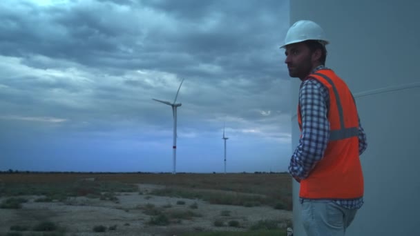 Na výšku: inženýr u větrných turbín rozvíjí ekologickou energii. Koncepce znečišťování životního prostředí, nové technologie alternativní energie. Všeobecný plán, večer, přetypování. — Stock video