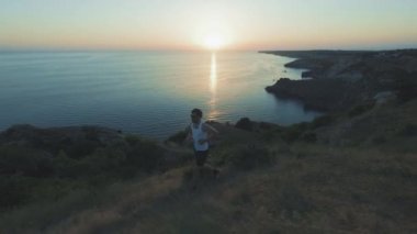 Athletic Handsome Man Telefon ve Kulaklık ile Spor yapıyor, Yaz plajda Jogging sırasında Günbatımında Sea Coast boyunca Çalışan. Kablosuz kulaklık kullanır.