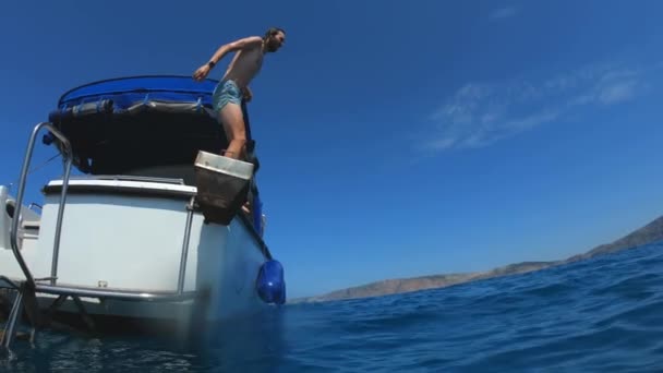 Guapo joven saltando de un barco o yate en el mar o el océano. Vacaciones de verano con amigos. Los turistas se divierten y bucean. Movimiento lento — Vídeos de Stock