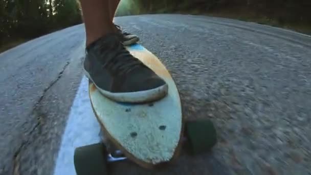 Close-up skateboarder dreng ridning udendørs. En ung mand kører langbord på motorvejen. Misty vej i skoven – Stock-video
