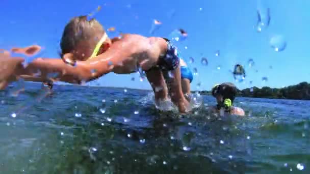 Mladý pohledný chlapec skáče do moře. Děti skáčou do moře somersaultů. Teenageři skáčou do vody. Plavat pod vodou a hrát. Letní zábava na moři — Stock video