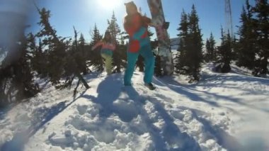 İki neşeli güzel genç kız snowboardcular veya kayakçılar bir kar drift oturan ve kar atma, gülümseyerek tadını çıkarın. Kadınlar kış karlı çam arasında duruyor. Kayak merkezinde kış eğlencesi. Yavaş çekim