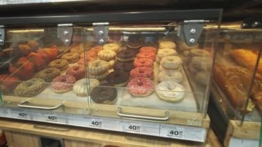 bir süpermarket veya fırında raflarda birçok donut.