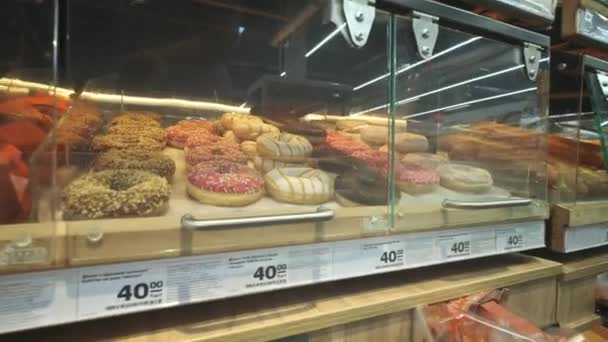 Muitos donuts em prateleiras em um supermercado ou padaria . — Vídeo de Stock