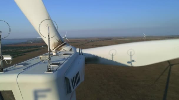 Gros plan d'une éolienne. L'éolienne aérienne de vue de dessus, se déplaçant au-dessus de la construction moderne blanche de l'éolienne est un dispositif qui convertit l'énergie cinétique des vents en énergie électrique — Video