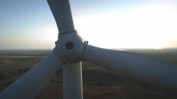 Feche uma turbina eólica. Aeronave vista superior turbina eólica, movendo-se acima da construção moderna branca da turbina eólica é dispositivo que converte a energia cinética dos ventos em energia elétrica — Vídeo de Stock