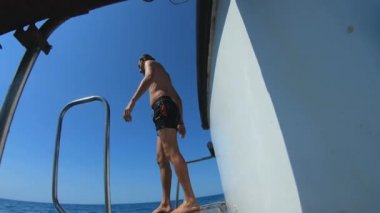 Yakışıklı genç adam bir tekne veya yattan denize ya da okyanusa atlıyor. Arkadaşlarıyla yaz tatili. Turistler eğlenir ve dalın. Yavaş çekim