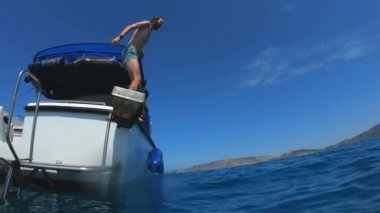 Yakışıklı genç adam bir tekne veya yattan denize ya da okyanusa atlıyor. Arkadaşlarıyla yaz tatili. Turistler eğlenir ve dalın. Yavaş çekim