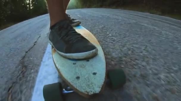 Close-Up gördeszkások fiú lovaglás kültéri. Egy fiatal férfi lovagol egy Longboard az autópályán. Ködös út az erdőben — Stock videók