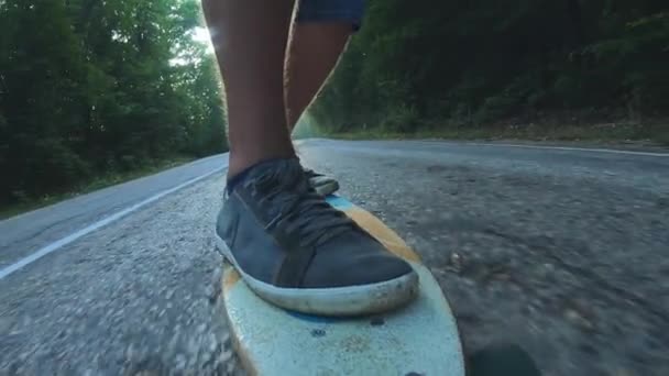 Närbild skateboardåkare pojke ridning utomhus. En ung man rider en longboard på motorvägen. Dimmig väg i skogen — Stockvideo