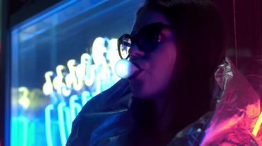 Kürk gözlük genç moda genç kız sokak neon mavi pembe işareti ile aydınlatılmış sakız üfleme, trendy gece ışık güzel bin yıllık kadın 80s kavramı geri kızdırma