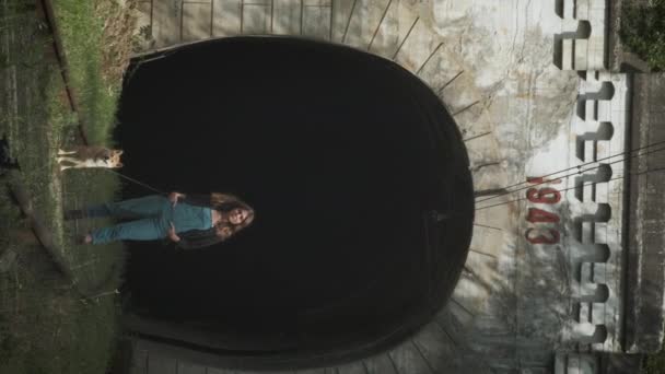 一个女孩站在旧隧道的背景上。一个带着狗的女孩站在铁轨上 — 图库视频影像