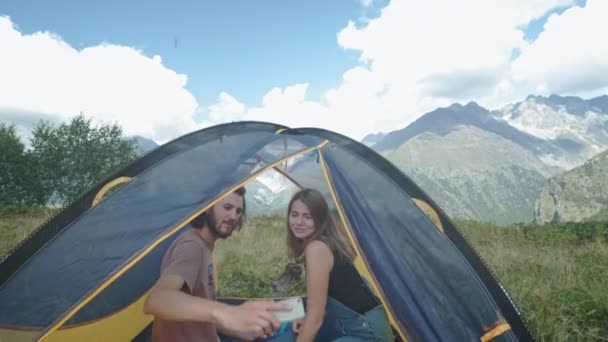Lyckliga par resenärer man och kvinna i ett tält ta Selfie på smartphone. Ta ett foto för sociala nätverk. Gult tält. Vandra i fjällen — Stockvideo