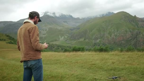 Un blogueur voyageur masculin contrôle un copter. Tenez la télécommande dans ses mains, filmez des vidéos sur un hélicoptère ou prenez des photos d'une hauteur. Nouvelles technologies dans la production vidéo — Video