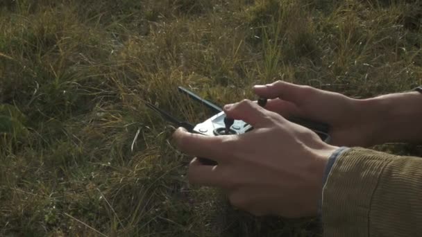 Drone télécommandé dans les mains masculines du pilote gros plan. Homme navigation drone volant avec télécommande. L'homme dans la nature à la campagne . — Video