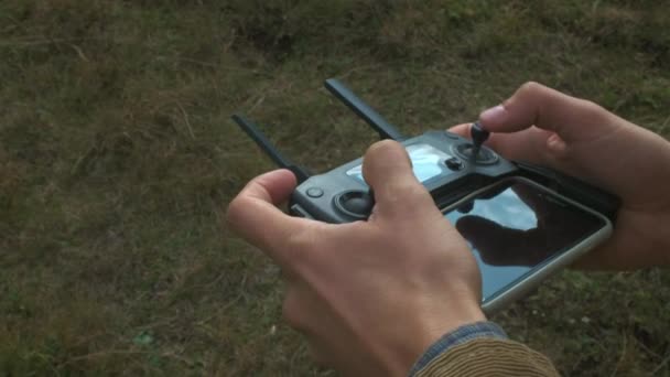 Ferngesteuerte Drohne in den Händen des Piloten aus nächster Nähe. Flugdrohne mit Fernbedienung. Mensch in der Natur auf dem Land. — Stockvideo