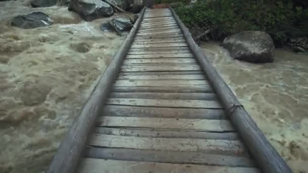 Un puente de madera sobre un río de montaña rápido — Vídeo de stock