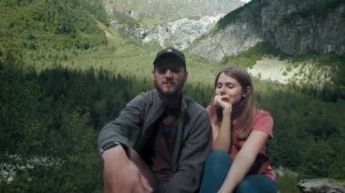 Dağlardaki mutlu çift gezgin erkek ve kadın akıllı telefonda selfie çekiyor. Sosyal ağlar için bir fotoğraf çekin. Dağlarda yürüyüş