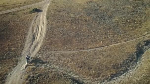 Antenne: Motorrad-Fahrer fährt auf sandigem Boden in der Wüste. Extremsport an malerischen Orten. Motocross in der Wüste. — Stockvideo