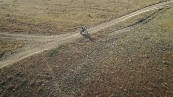AERIAL: мотоцикліст їде на піщаному ґрунті в пустелі. Екстремальні види спорту в мальовничих місцях. Мотокрос в пустелі . — стокове відео