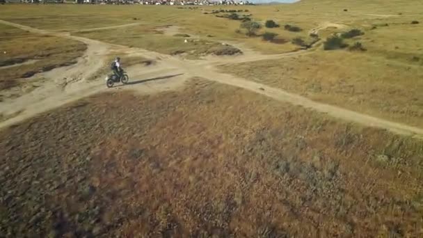 Aerial: motorrijder rijdt op het zandgrond in de woestijn. Extreme sporten op pittoreske plaatsen. Motocross in de woestijn. — Stockvideo