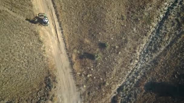 AERIAL: passeio de motociclista no solo arenoso no deserto. Esportes radicais em lugares pitorescos. Motocross no deserto . — Vídeo de Stock