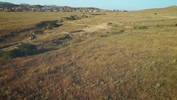 AERIAL: paseos en moto por el suelo arenoso del desierto. Deportes extremos en lugares pintorescos. Motocross en el desierto . — Vídeo de stock