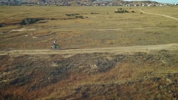 Aerial: motorrijder rijdt op het zandgrond in de woestijn. Extreme sporten op pittoreske plaatsen. Motocross in de woestijn. — Stockvideo