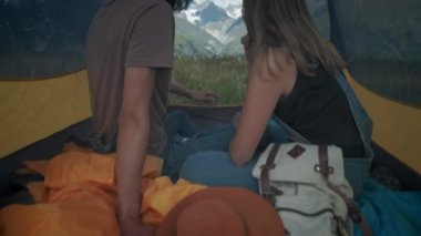 Çadırda birkaç erkek ve kadın yolcu. Küçük parmaklarınızla tutun, bir kavgadan sonra barış. Romantik bir eğlence. Arka planda karla kaplı dağlar