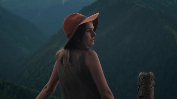 山への旅に興奮した帽子をかぶったヒップスターの女の子のバックビュー、自然に近い自由と幸せを感じるアルプスのピークを探す幸せな若い女性. — ストック動画