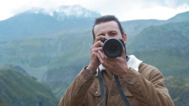 Porttait: Erkek gezgin fotoğrafçı blog için profesyonel dağlar resimleri yapar. Elinde profesyonel bir kamera tutan uzun saçlı ve sakallı bir adam. Dağlara sefer.