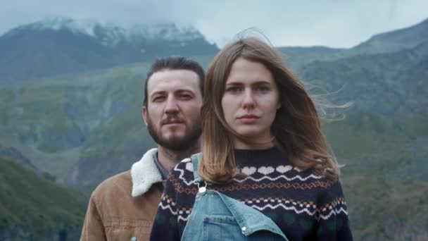 RETRATO: Casal de homens e mulheres viajantes em um fundo de montanhas. Vestido com camisolas quentes do norte. Aventuras nas montanhas nevadas — Vídeo de Stock